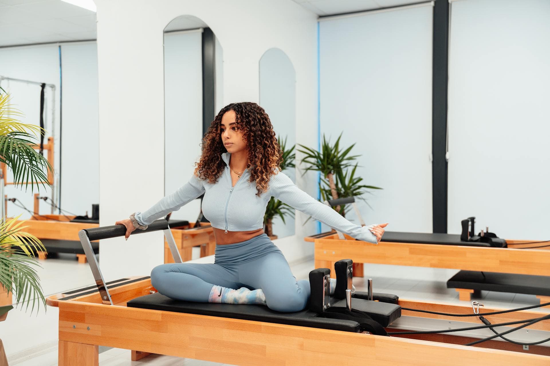 Alumna en posición de equilibrio sobre Reformer en Aura Pilates Studio, Horta-Guinardó Barcelona